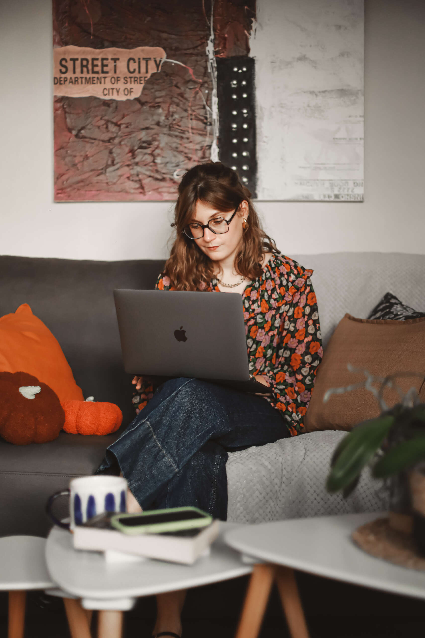une femme regarde son ordinateur portable assise sur un canapé