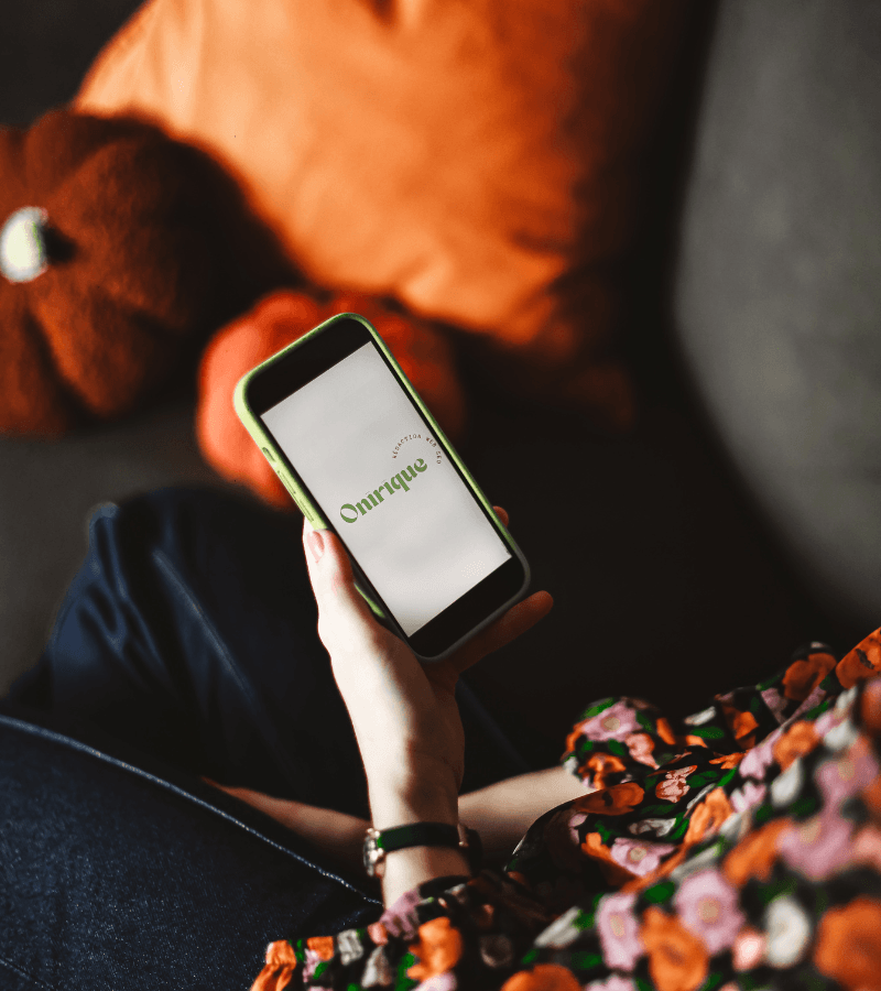 une femme assise sur un canapé tenant un téléphone dans sa main